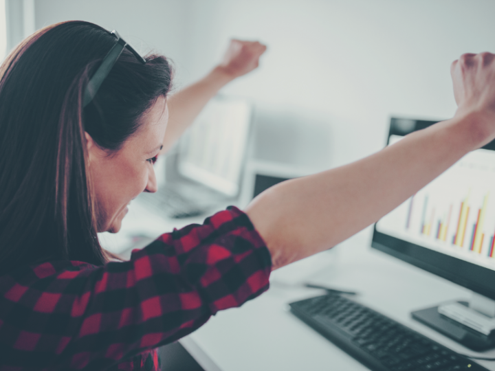 tevreden vrouw met armen in de lucht aan een computerscherm